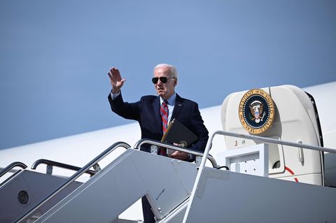 US-Pärsident Joe Biden steht auf der Gangway der Air Force One und winkt. Er trägt Anzug und Sonnenbrille sowie eine Mappe