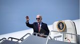 US-Pärsident Joe Biden steht auf der Gangway der Air Force One und winkt. Er trägt Anzug und Sonnenbrille sowie eine Mappe