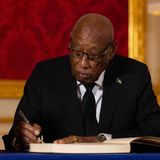 Cornelius A. Smith, ein dunkelhäutiger Mann mit kurz rasiertem Haar schreibt im schwarzen Anzug in ein Kondolenzbuch