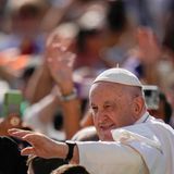 Papst Franziskus winkt in weißem Gewand mit links in eine Menschenmenge