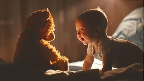 Ein Baby spielt mit einem Teddy.
