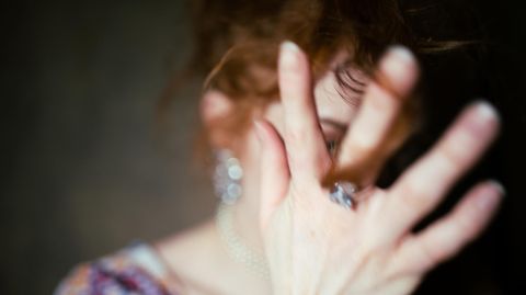 Eine Frau hält ihre Hand vor das Gesicht