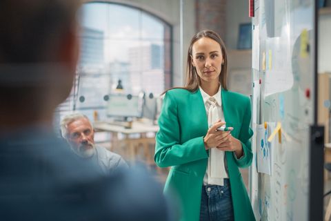 Eine Frau steht in einem Büro – umgeben von zwei Männern.
