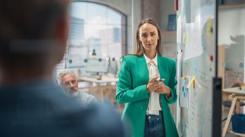 Eine Frau steht in einem Büro – umgeben von zwei Männern.