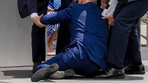 US-Präsident Joe Biden kniet nach einem Sturz im Anzug auf einer Bühne