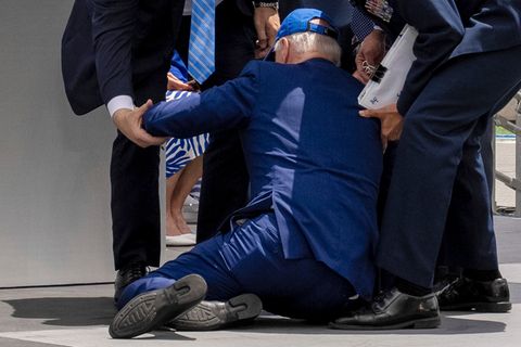 US-Präsident Joe Biden kniet nach einem Sturz im Anzug auf einer Bühne