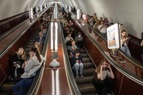 Menschen sitzen auf einer Rolltreppe während sie in einer Metrostation in Kiew Schutz suchen