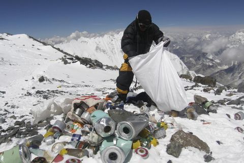 Ein Mensch in warmer Kleidung sammelt am Mount Everest Müll in einen weißen Sack