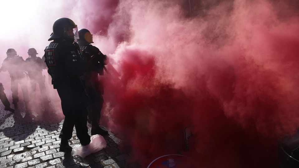 Am Tag X in Leipzig sind behelmte Polizisten in roten Rauch eingehüllt