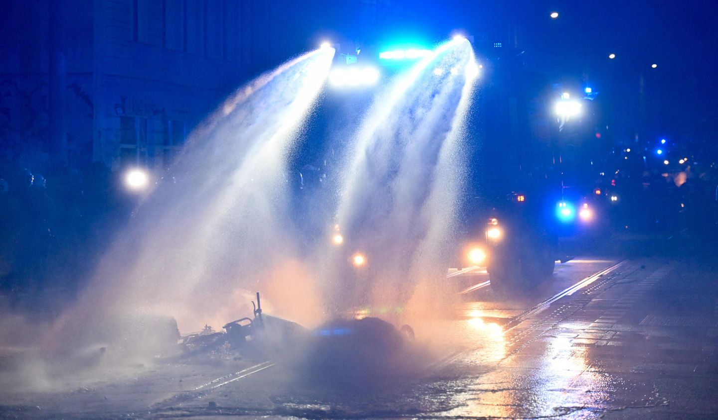 Ein Wasserwerfer der Polizei löscht eine brennende Barrikade im Stadtteil Connewitz. Unweit davon wurden nach Polizeiangaben eine Polizeiwache mit Steinen beworfen und weitere Barrikaden angezündet.