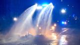 Ein Wasserwerfer der Polizei löscht eine brennende Barrikade im Stadtteil Connewitz. Unweit davon wurden nach Polizeiangaben eine Polizeiwache mit Steinen beworfen und weitere Barrikaden angezündet.