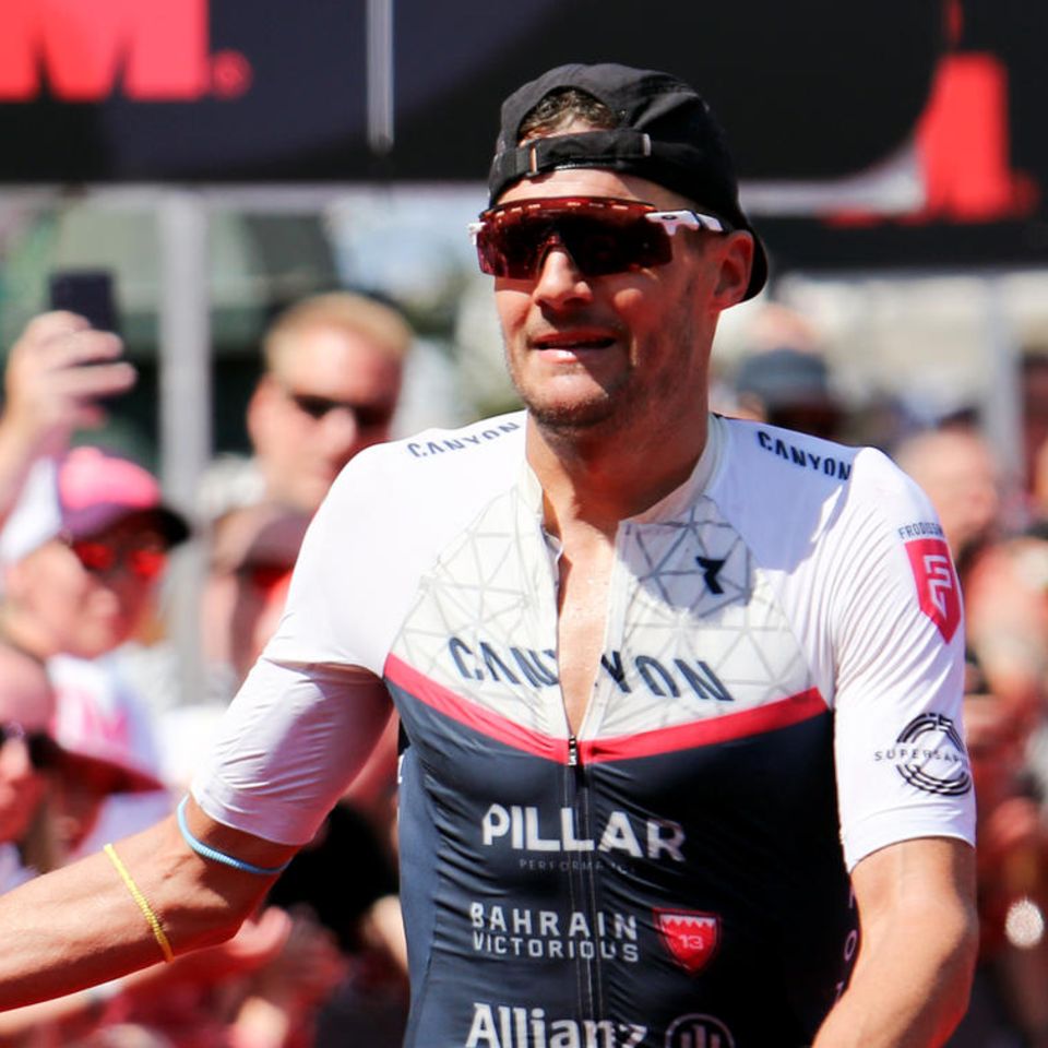 Triathlet Jan Frodeno klatscht im Ziel beim Ironman in Hamburg mit Zuschauern ab