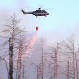 Ein Löschhubschrauber wirft Wasser ab über einem Waldbrand in einem munitionsbelasteten Gebiet bei Jüterbog