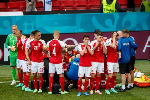Fußballspieler stehen im Kreis um einen Mitspieler, der reanimiert wird