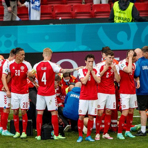 Fußballspieler stehen im Kreis um einen Mitspieler, der reanimiert wird