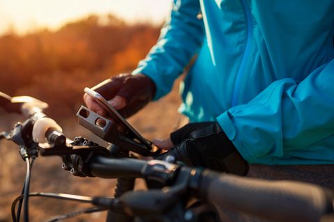 Ein Mann klemmt sein Smartphone in die Handyhalterung mit Powerbank am Fahrrad