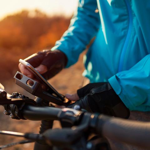 Ein Mann klemmt sein Smartphone in die Handyhalterung mit Powerbank am Fahrrad