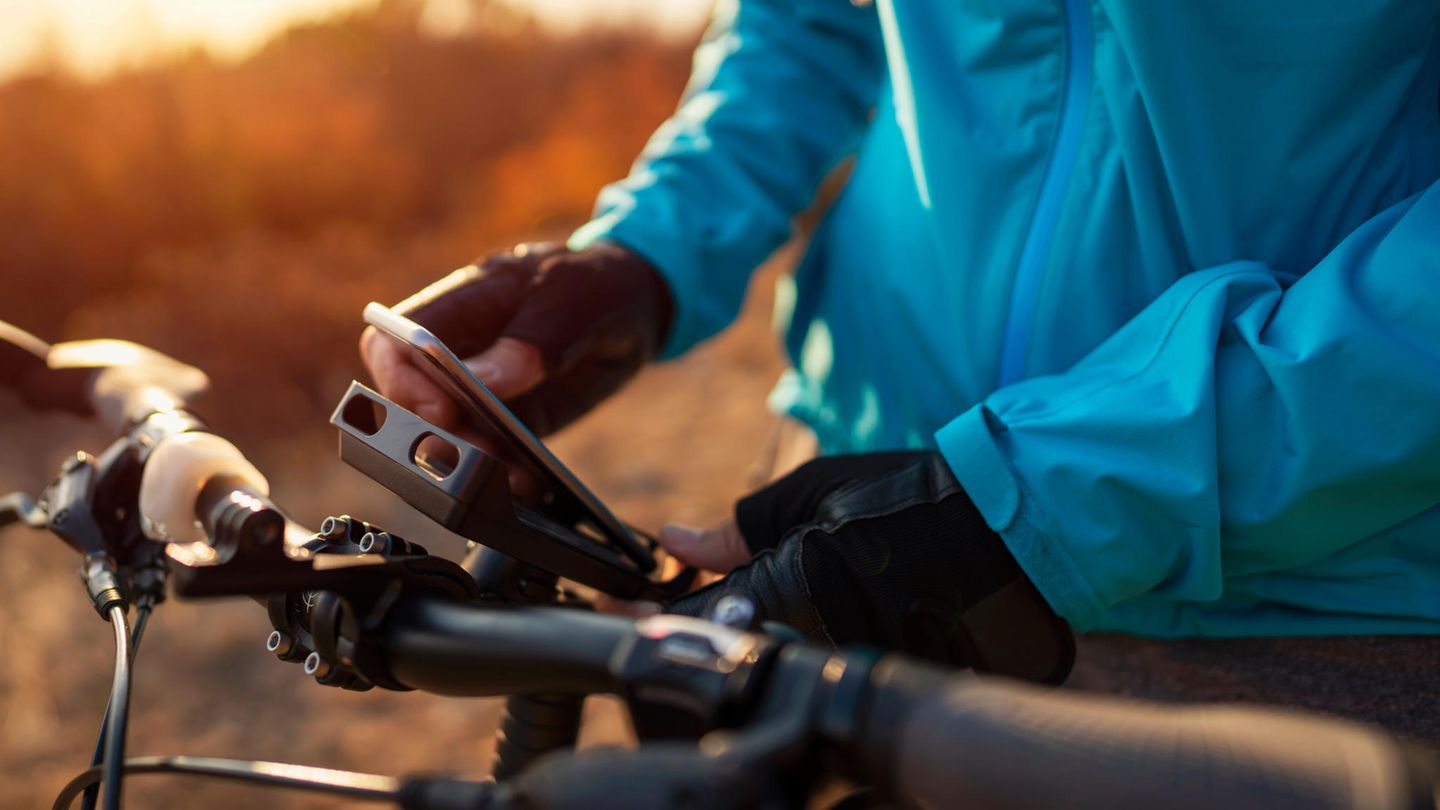 Ein Mann klemmt sein Smartphone in die Handyhalterung mit Powerbank am Fahrrad