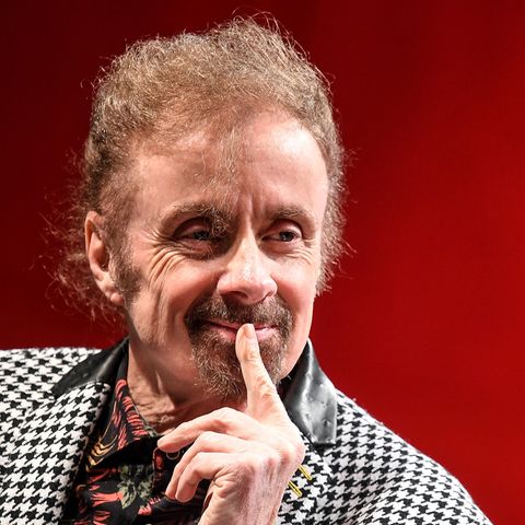 T. C. Boyle hält einen Finger an die Lippen und lächelt