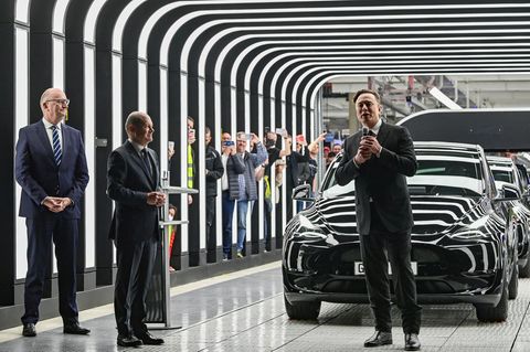 Dietmar Woidke, Olaf Scholz und Elon Musk stehen vor einem Auto in der Tesla-Fabrik in Brandenburg