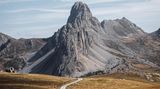 Ein schmaler Radweg schlängelt sich durch die französischen Alpen, die im Sommer schroff grau erscheinen. Ohne Schnee