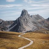 Ein schmaler Radweg schlängelt sich durch die französischen Alpen, die im Sommer schroff grau erscheinen. Ohne Schnee