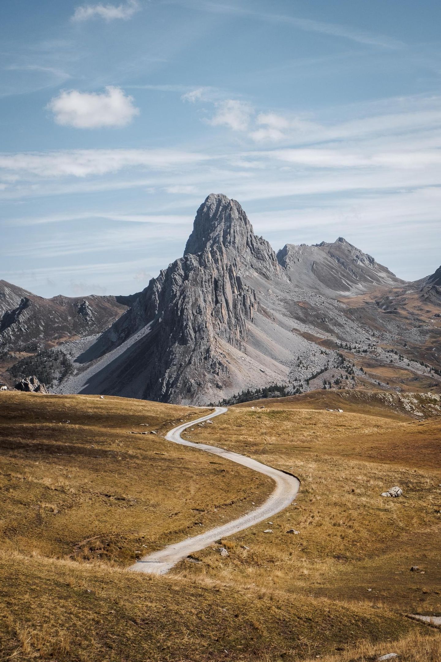 Ein schmaler Radweg schlängelt sich durch die französischen Alpen, die im Sommer schroff grau erscheinen. Ohne Schnee