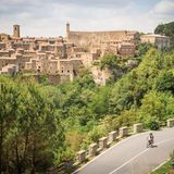 Ein Radfahrer fährt an einem Bergdorf aus dem Mittelalter vorbei