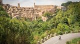 Ein Radfahrer fährt an einem Bergdorf aus dem Mittelalter vorbei