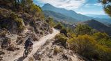 Ein Radfahrer fährt durch die Berge in Andalusiens, in der Ferne ragt ein Gipfel heraus
