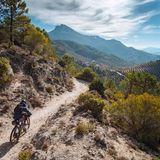 Ein Radfahrer fährt durch die Berge in Andalusiens, in der Ferne ragt ein Gipfel heraus