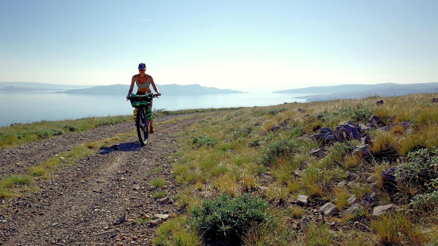 Eine Frau auf einem Mountainbike fährt in Kroatien an der Adria entlang