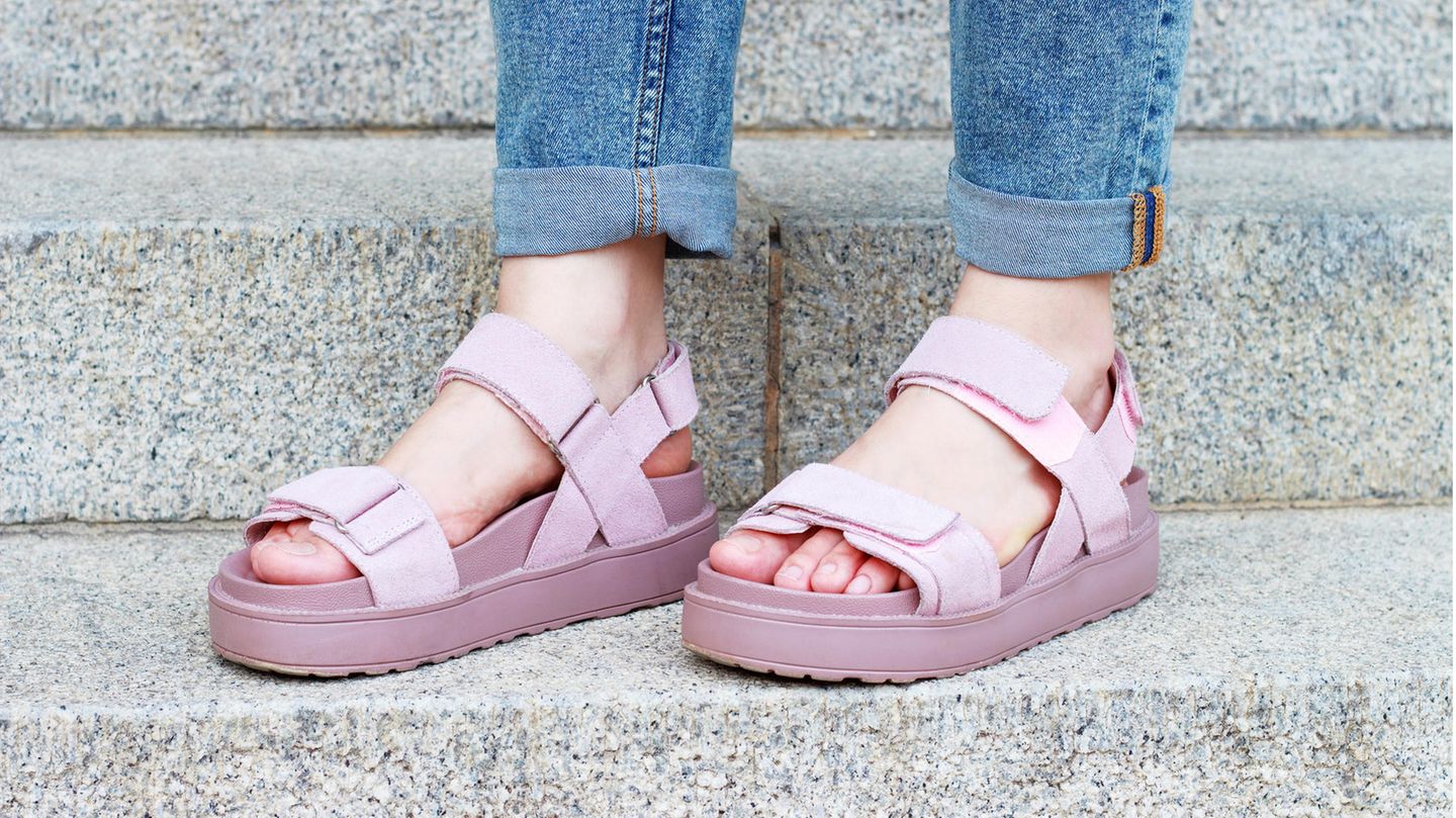 Weibliche Füße in rosa Sandalen auf Betontreppe