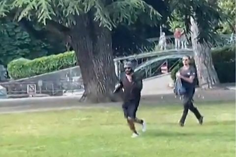 Ein Mann flieht mit einem Messer bewaffnet über den Rasen an einem Spielplatz in Annecy, Frankreich