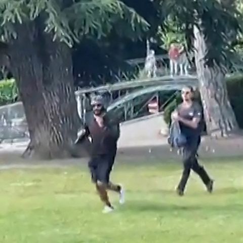 Ein Mann flieht mit einem Messer bewaffnet über den Rasen an einem Spielplatz in Annecy, Frankreich