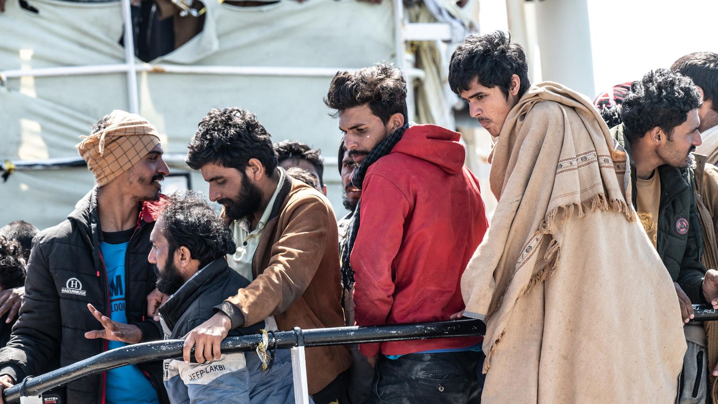 Geflüchtete gehen in Italien von Bord eines Schiffes um Asyl zu beantragen