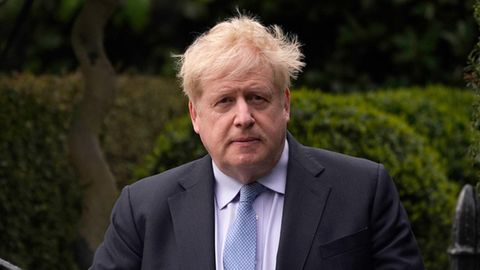 Boris Johnson verlässt sein Haus. Er trägt eine hellblaue Krawatte, ein weißes Hemd und ein dunkelblaues Jackett