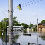 Fast trotzig weht eine ukrainische Flagge über den Wassermassen in Cherson