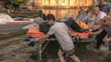 Helfer bringen einen alten Mann auf einer Trage in Sicherheit