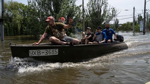 Freiwillige evakuieren Kinder in einem Boot aus einem überfluteten Stadtteil von Cherson.
