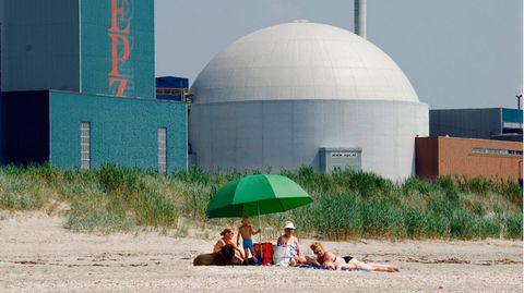 Drei Frauen mit Kindern und einem Hund liegen am Strand vor dem Atomkraftwerk Borssele