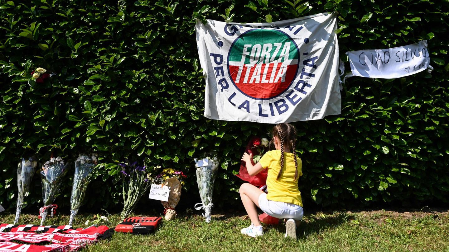 Von Meloni bis Draghi: Ein Mädchen legt außerhalb von Berlusconis Villa in Rom Blumen nieder. Ein Mädchen legt außerhalb von Berlusconis Villa in Rom Blumen nieder.