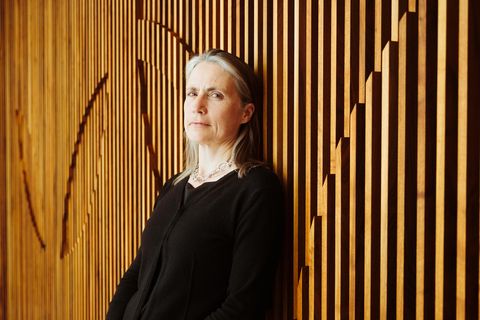 Fiona Hill lehnt an einer Holzwand