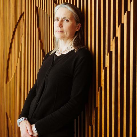 Fiona Hill lehnt an einer Holzwand