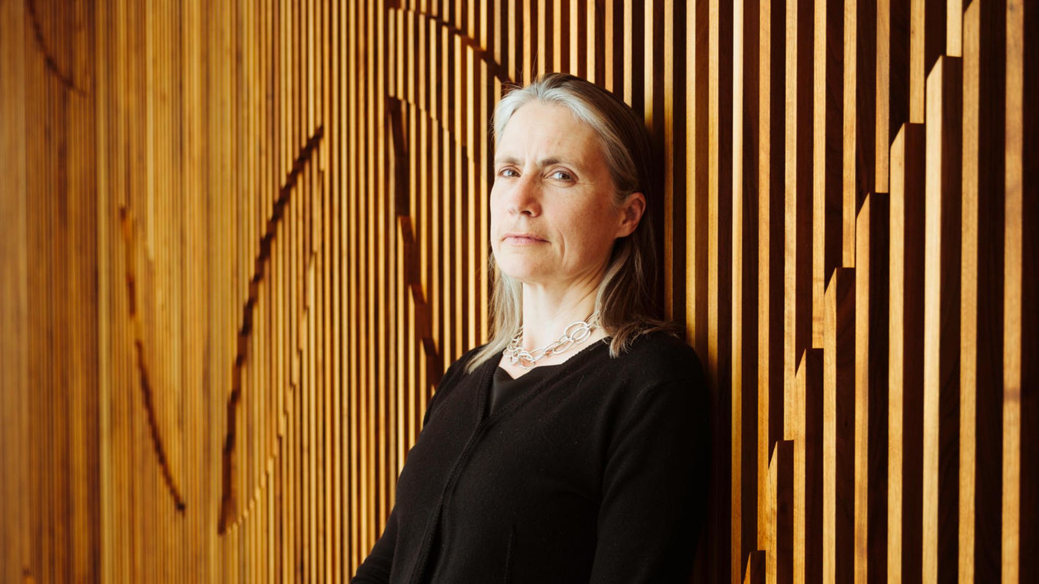 Fiona Hill lehnt an einer Holzwand