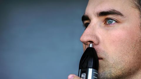 Nasenhaare entfernen: Ein Mann nutzt einen Trimmer, um seine Nasenhaare zu entfernen