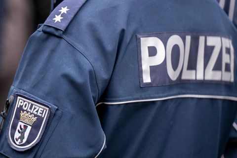 Auf einer dunkelblauen Jacke ist auf einem Ärmel das Wappen der Polizei Berlin und auf dem Rücken ein "Polizei"-Schriftzug