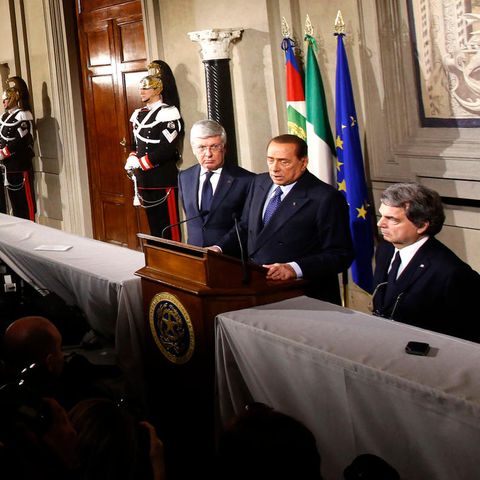 Silvio Berlusconi steht an einem Rednerpult