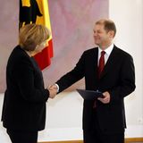 Angela Merkel schüttelt Olaf Scholz die Hand, Franz Müntefering steht daneben