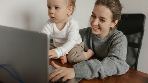 Eine Frau sitzt mit einem kleinen Kind vor einem Laptop